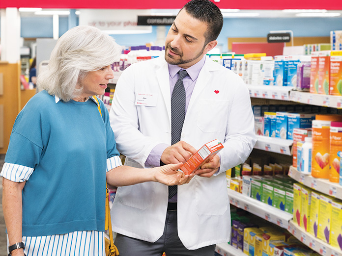 Image of a pharmacist helping an older lady pick out a prescription in an aisle of a CVS