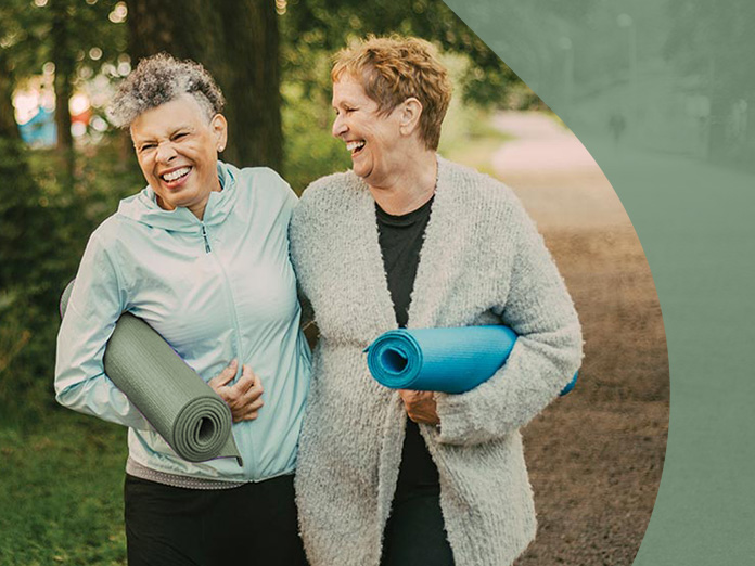 Two people carrying yoga mats while walking in the park