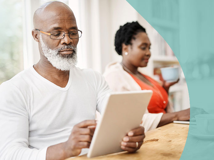 A person sitting next to another looking at the Aetna provider directory on their laptop and tablet