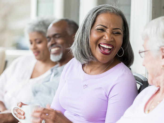 Woman in a purple shirt smiling and talking about Medicare Advantage HMO plans to a woman with glasses
